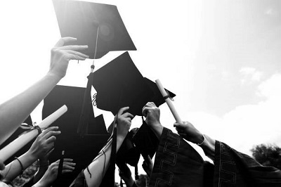 Group of graduate students throwing graduation hats to the sky.